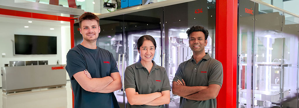 A group of SOMIC APAC employees in front of a SOMIC carton packaging machine in the Bangkok office
